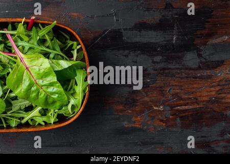 Rucola raab e Mangold, bietola svizzera, su vecchio tavolo di legno scuro sfondo, vista dall'alto piatto, con spazio copia per il testo Foto Stock