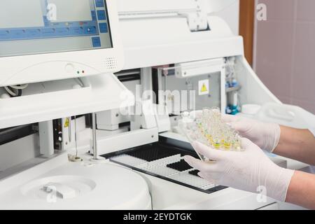 Lab tech il caricamento di campioni in un analizzatore per chimica Foto Stock