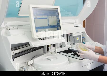 Lab tech il caricamento di campioni in un analizzatore per chimica Foto Stock