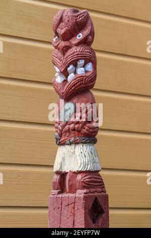 Una scultura in legno neozelandese Maori raffigurante la figura stilizzata di un guerriero che tiene un randello di greenstone Foto Stock
