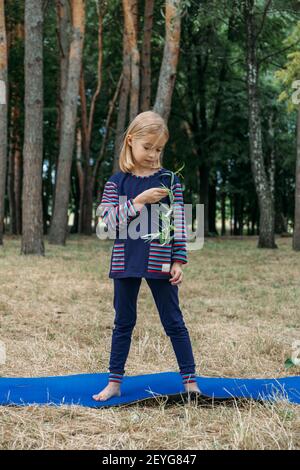 Educazione ambientale per i bambini. Bambina che tiene la pianta giovane in mani contro sfondo albero verde. Ambiente, sostenibilità, giorno della terra Foto Stock