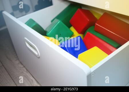 Cubi multicolore in un cassetto di un armadio in una stanza per bambini. Box giochi per bambini con giocattoli per costruzioni. Cubi per bambini per il gioco. Foto Stock