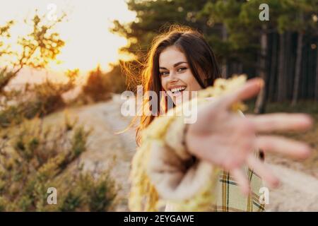 donna felice in natura mostra la sua palma e ride vicino alberi di conifere Foto Stock