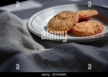 Biscotti di farinata d'avena per colazione su un piatto bianco. Colazione sana, tovaglia crumpled. Foto Stock