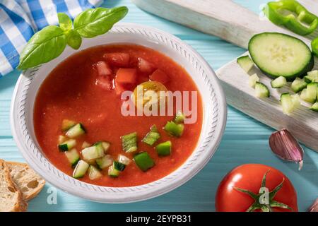 Gazpacho Andaluz è una zuppa fredda di pomodoro andalusa di Spagna con cetrioli, aglio, pepe su sfondo azzurro Foto Stock