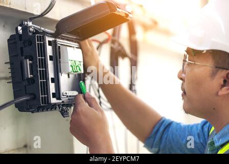 Connettore di riparazione tecnico le fibre sul vassoio splitter in primo piano all'esterno Foto Stock