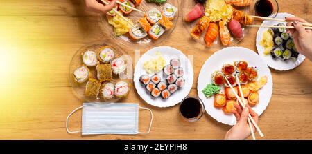 Banner. Festa con cena a domicilio a Lockdown in pandemia con sushi giapponese dal servizio di consegna o da asporto. Vari salmoni, granchio, involtini vegani, wasabi Foto Stock