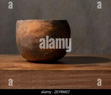 Una semplice ceramica rustica fatta a mano con argilla, bruciata a fuoco, per trattenere acqua o cucinare, su sfondo di legno, marrone, due pezzi, vista laterale Foto Stock