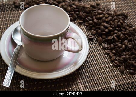 Una tazza vuota di caffè e chicchi di caffè su un tappeto di bambù Foto Stock