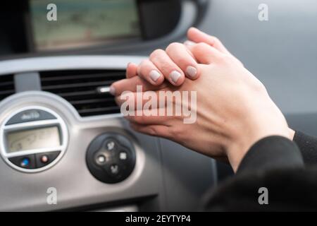 La donna sta sfregando le mani sul riscaldatore dell'automobile. Mani fredde sull'aria calda. Foto Stock
