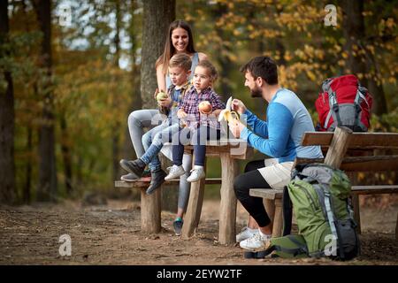 Giovane famiglia con bambini che hanno uno spuntino di frutta in gita Foto Stock