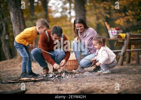 Genitori giovani con bambini piccoli che preparano il fuoco in legno Foto Stock