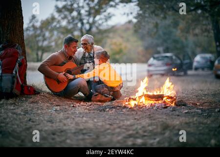 Nonni con nipote al picnic godendosi con la chitarra Foto Stock