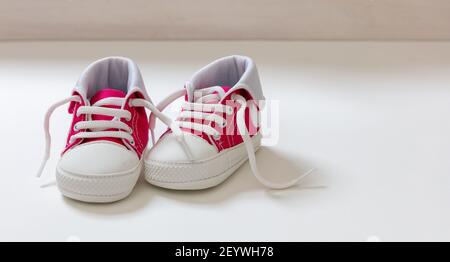 Scarpe sportive baby girl su sfondo bianco. Scarpe da ginnastica rosa per bambini di piccole dimensioni, vista in primo piano con stivaletti in tela. Spazio, modello invito scheda Foto Stock