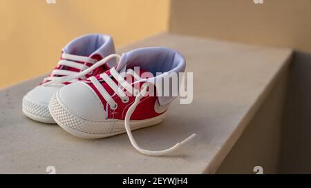 Scarpe sportive per bambini colore rosa rosso su pavimento bianco, sfocatura sfondo esterno. Scarpe da ginnastica per bambini di piccole dimensioni, bambini attivi Foto Stock