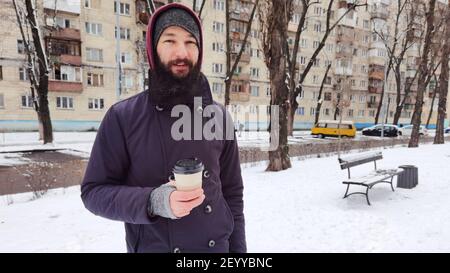 Primo piano ritratto di un giovane bearded che beve caffè da asporto. Uomo che beve caffè Foto Stock