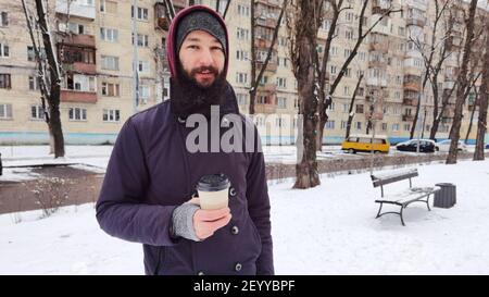 Primo piano ritratto di un giovane bearded che beve caffè da asporto. Uomo che beve caffè Foto Stock