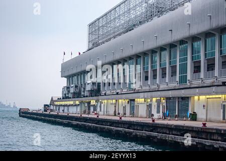 Kowloon, Hong Kong, Cina - 13 Maggio 2010: Il molo del Terminal Empty Ocean sotto la luce serale ospita un grande edificio per lo shopping. Green Victoria Harbour wat Foto Stock