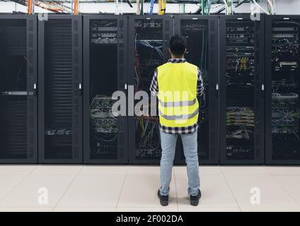 Ingegnere informatico maschile che lavora all'interno del database della sala server Foto Stock