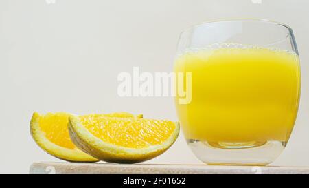 Versare la limonata gialla in un bicchiere trasparente con le fette di arance. Succo giallo, bevanda all'arancia. Foto Stock