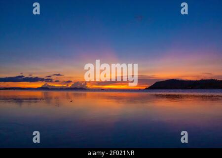 Meraviglioso paesaggio del tramonto sulla riva, colori del cielo del tramonto e silhouette dell'isola in acqua. Incredibile tramonto tropicale. Foto Stock