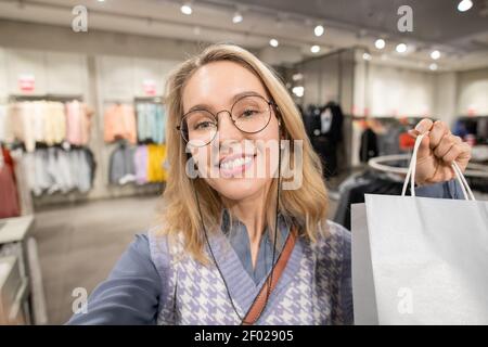 Ritratto di giovane donna con borse sorridenti alla macchina fotografica dopo aver fatto acquisti di successo Foto Stock