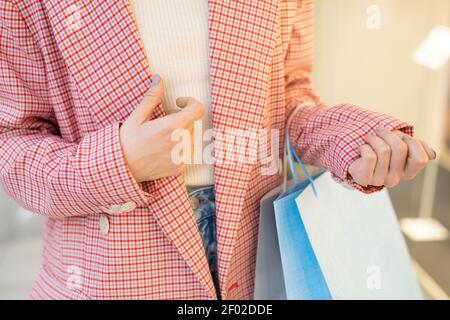 Primo piano di donna in elegante giacca che tiene borse per la spesa Foto Stock