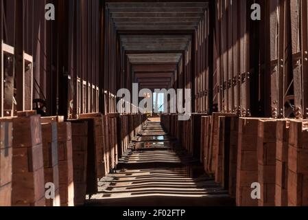 Un lungo corridoio nell'edificio industriale con ombre di le colonne sul terreno Foto Stock