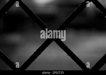 Uno shot di primo piano in scala di grigi dei tubi incrociati di a. reticolo con sfondo sfocato Foto Stock