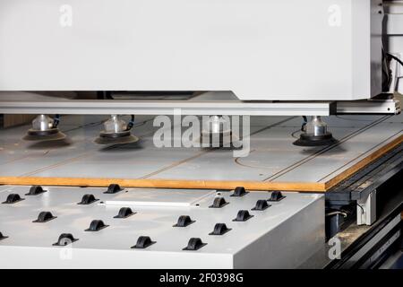 Il meccanismo a rulli di una moderna segatrice per legno funziona in combinazione con una serie di ventose pneumatiche in gomma sulla linea di alimentazione del truciolato. Foto Stock