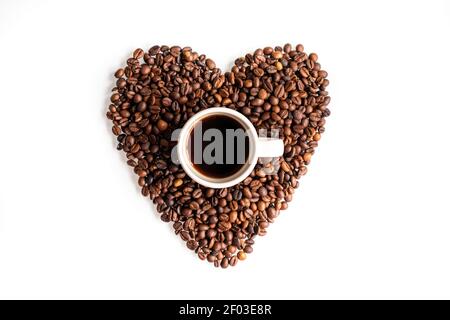 Una pausa per gli amanti del caffè. Una tazza di caffè all'interno di un cuore fatto di chicchi di caffè. Composizione piatta su sfondo bianco. Foto Stock