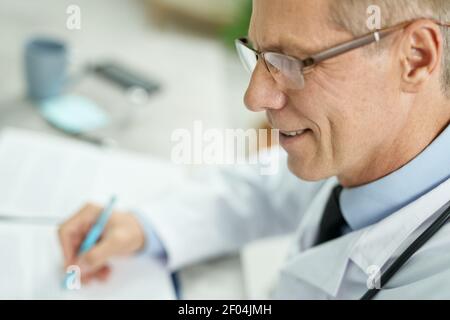 Allegro medico maschile in occhiali che lavorano in clinica Foto Stock