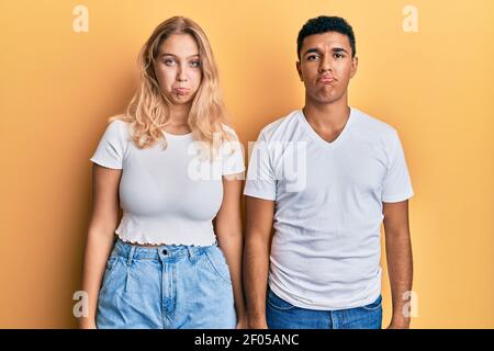 Giovane coppia interracial che indossa casual tshirt bianca depressa e preoccupazione per disagio, piangendo arrabbiato e paura. Espressione triste. Foto Stock