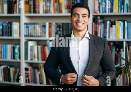 Ritratto di un bel leader aziendale, freelance o studente guarda direttamente alla fotocamera e sorridente amichevole. Manager di successo in elegante tuta formale, mostrare fiducia in se stessi Foto Stock