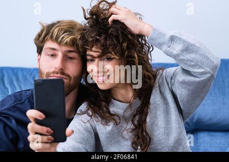 Giovane uomo barbuto vicino a donna sorridente in abiti casual prendendo selfie sul telefono cellulare Foto Stock