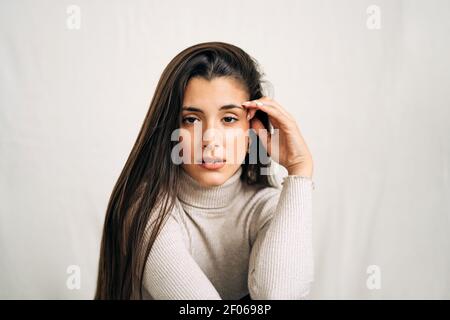 Donna giovane e premurosa che guarda la telecamera sullo sfondo dello studio di giorno Foto Stock
