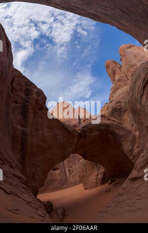 Vista pittoresca della formazione rocciosa ad arco situata tra ruvide scogliere In una zona arida di parco nazionale in USA contro nuvoloso cielo Foto Stock