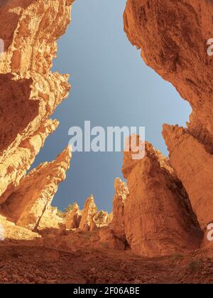 Da sotto di alte scogliere rocciose con superficie irregolare situata In un terreno arido contro il cielo senza nuvole nel soleggiato canyon di Bryce Negli Stati Uniti Foto Stock