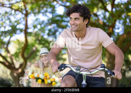 felice coppia che si inseguono a vicenda in bicicletta Foto Stock