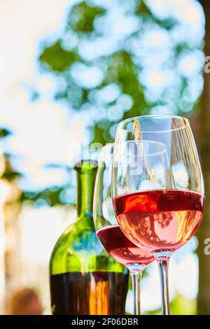 Due bicchieri ripieni di vino rosso e bottiglia sullo sfondo Foto Stock