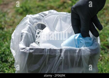 Mano dell'uomo mentre maschera protettiva del cestino su cestino separato,covid19 rifiuti di smaltimento medico Foto Stock