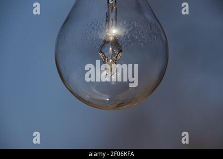 Primo piano di una lampadina vintage appesa all'aperto con condensa goccioline all'interno Foto Stock