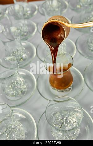 Versare il caffè turco nella tradizionale coppa goffrato. Foto Stock