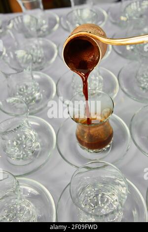 Versare il caffè turco nella tradizionale coppa goffrato. Foto Stock