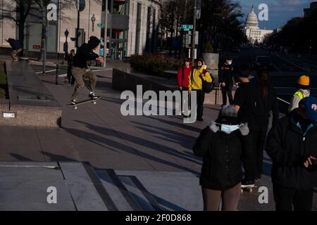 Washington, Stati Uniti. 06 marzo 2021. Skateboarders e pedoni in Freedom Plaza con il Campidoglio degli Stati Uniti visto sullo sfondo, a Washington, DC, sabato 6 marzo, 2021, in mezzo alla pandemia del coronavirus. Il Senato ha approvato il progetto di legge del Presidente Biden, da 1.9 trilioni di dollari, sulla COVID con alcune modifiche alla precedente versione della Camera di oggi, dopo molteplici sessioni notturne e intensi negoziati di questa settimana. (Graeme Sloan/Sipa USA) Credit: Sipa USA/Alamy Live News Foto Stock