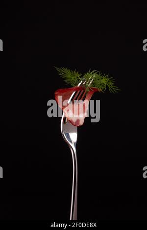 Pezzi di carne affumicata fredda stung su una forchetta di metallo Foto Stock