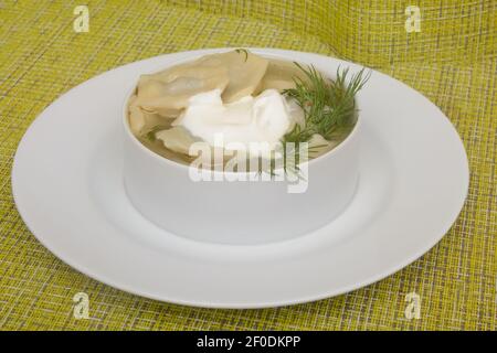 Cucina tradizionale russa e Ucraina. Gnocchi fatti in casa con panna acida e aneto verde. Primo piano, messa a fuoco selettiva. Foto Stock