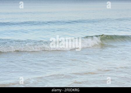 Onde di mare con rotoli di schiuma bianca sulla riva. Bella stagione, umore estivo. Foto Stock