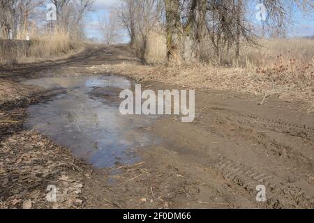 Grande puddle su strada sterrata all'inizio della primavera. Ostacolo per l'auto. Trasportare i cingoli degli pneumatici. Foto Stock