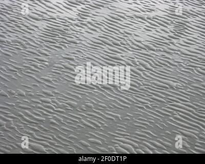 Increspature fatte da sabbia e acqua in un modello astratto sul letto di mare sulla sabbia Foto Stock